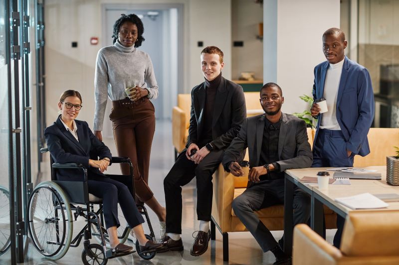 Em um escritório, uma equipe é composta por pessoas negras, brancas, uma cadeirante e uma pessoa LGBTQIA+