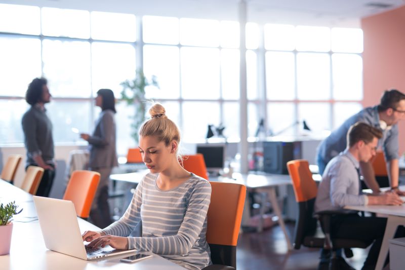 Empregos remotos: vários funcionários trabalhando em coworking lado a lado em modelo híbrido.