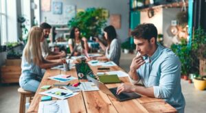 Profissional em coworking lendo no computador sobre clt e pj.